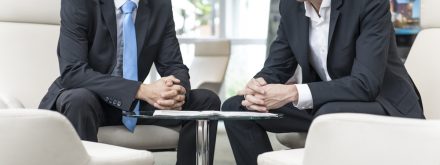 Esprit d’équipe — Cinq collaborateurs échangent dans un salon d’accueil, ambiance conviviale en entreprise