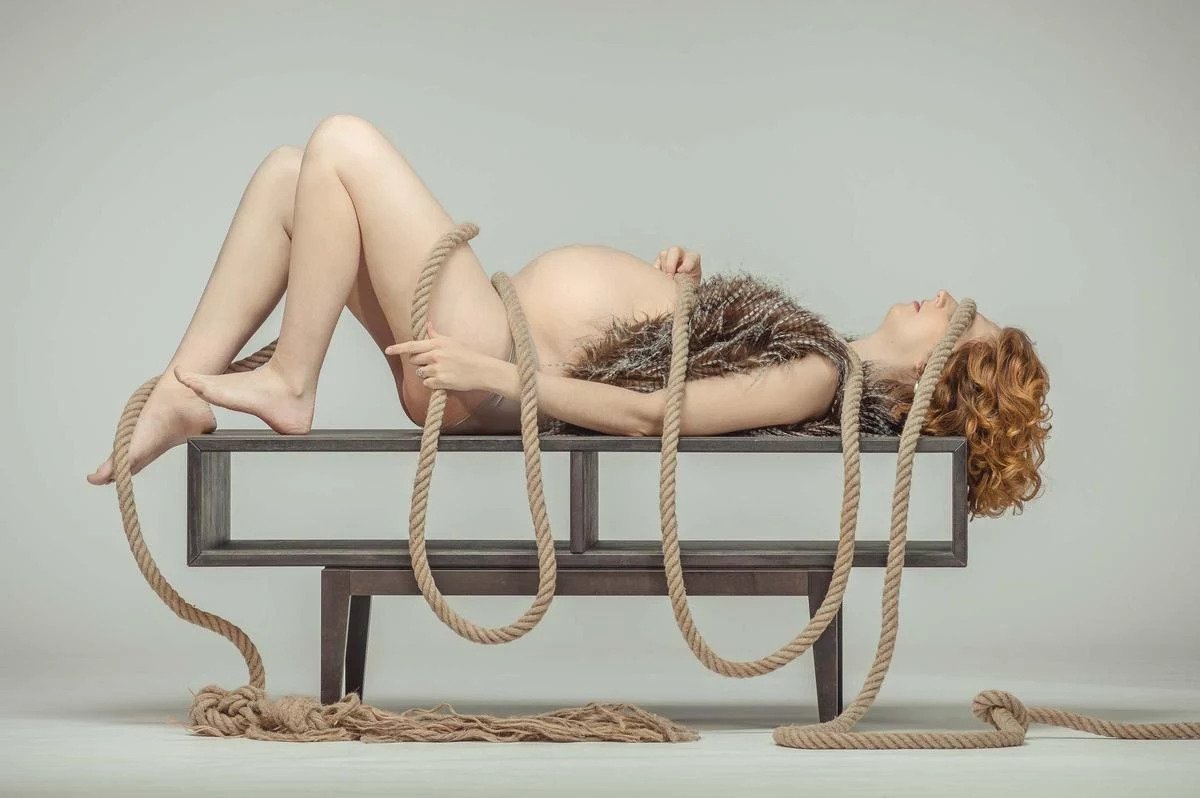 book photo studio à Lyon, Portrait d'une femme enceinte allongée sur une table et enroulée dans une grosse corde