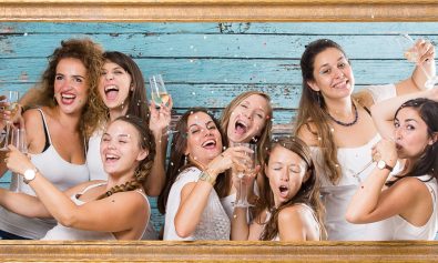 Un groupe de femme girly fêtent leur EVJF dans un studio photo avec une coupe de champagne à la main