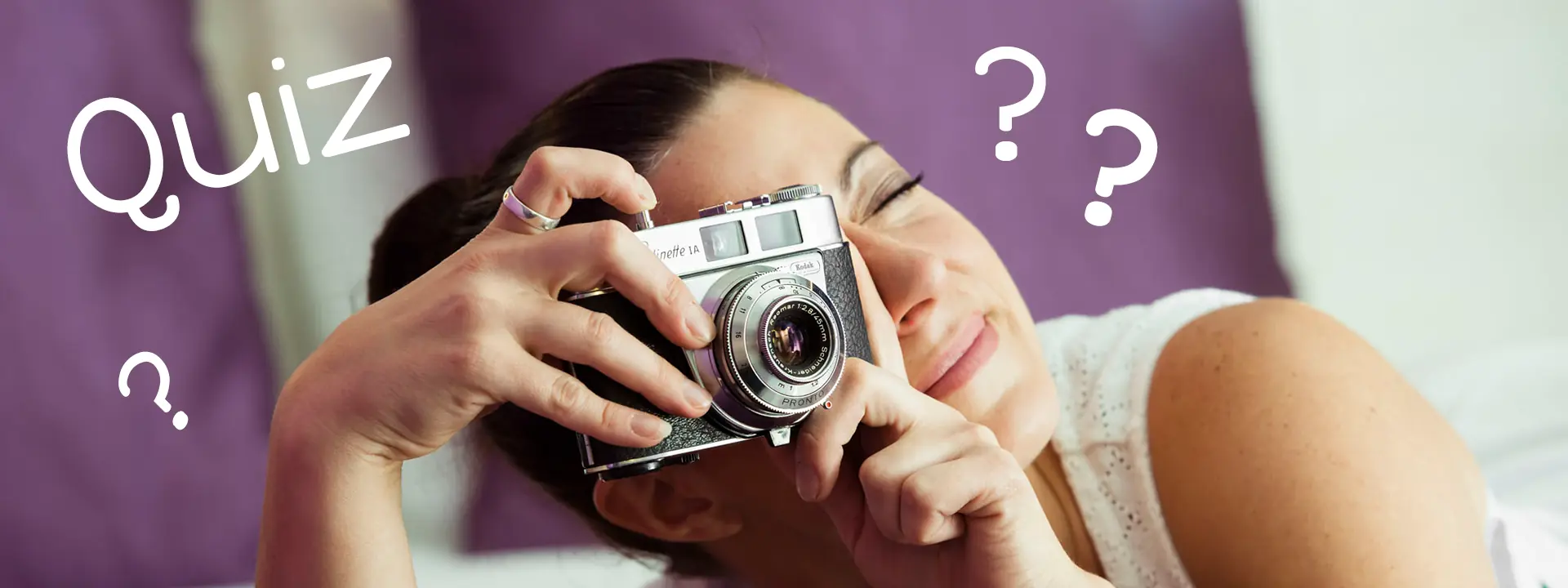 Femme qui souhaite apprendre la photo avec un jeu de quiz photo allongée sur son lit avec un appareil photo numérique dans les mains, question sur la photographie, test de connaissance photo, qcm photo numérique